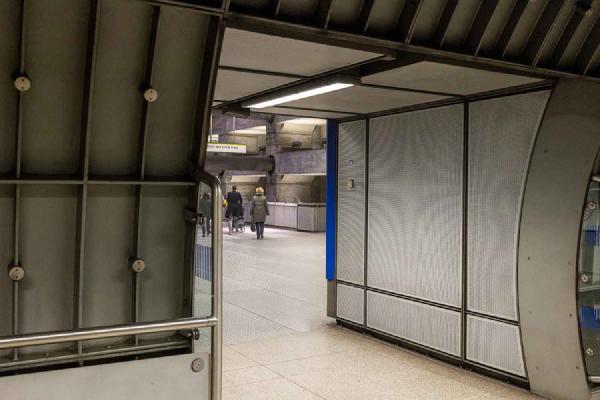 A view through a doorway into the atrium of Westminster underground station. People walk away.